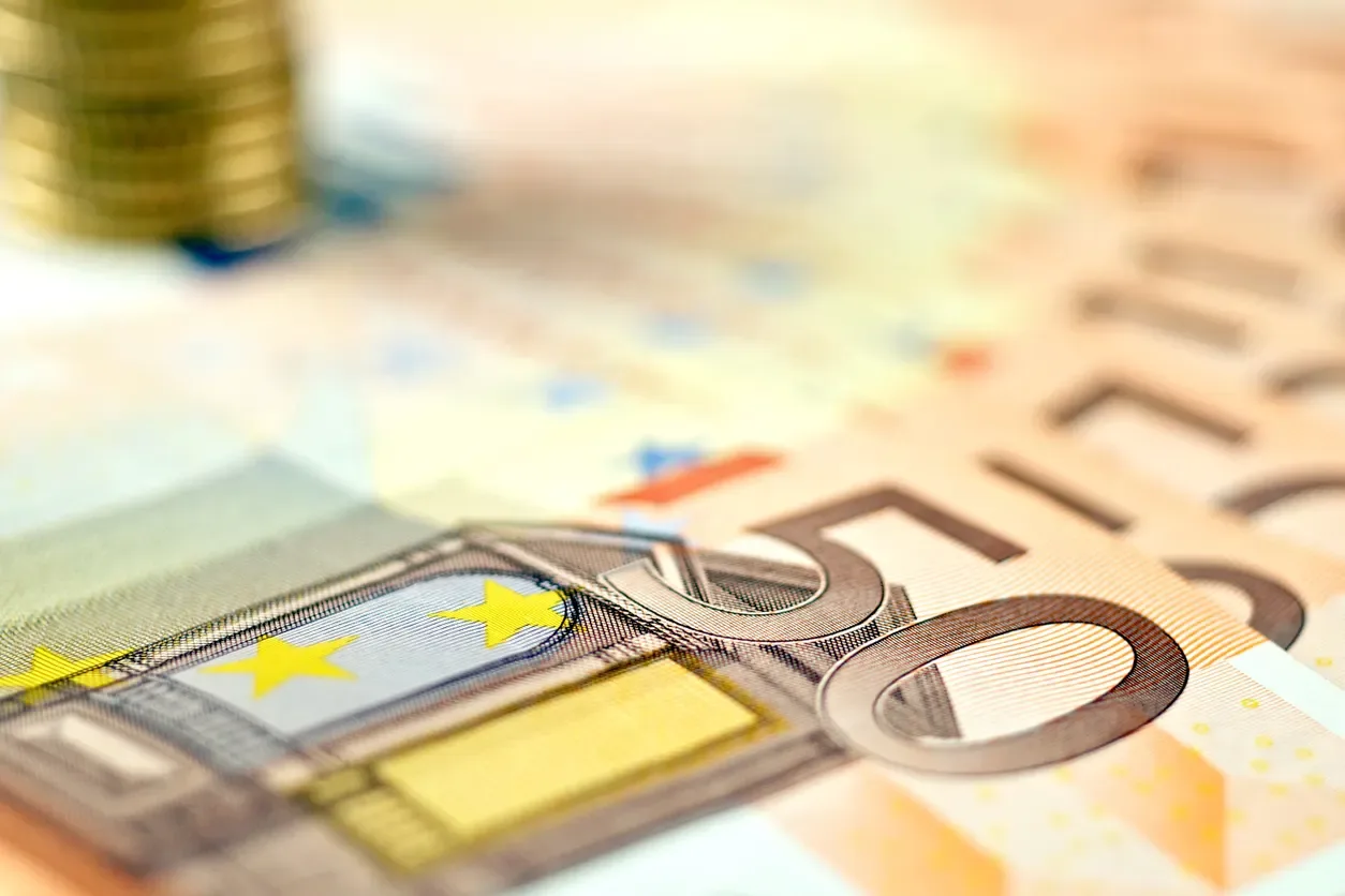 Cartões e notas em destaque sobre uma mesa, com moedas e cédulas ao fundo, sugerindo planejamento financeiro e tecnologia de pagamento no contexto de Split payment