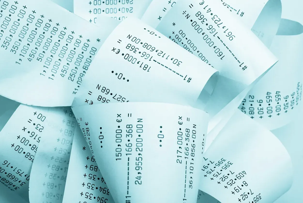Pilha de notas fiscais em folhas impressas com códigos e números, sugerindo documentos financeiros e fiscais no contexto da nota fiscal na reforma tributária.