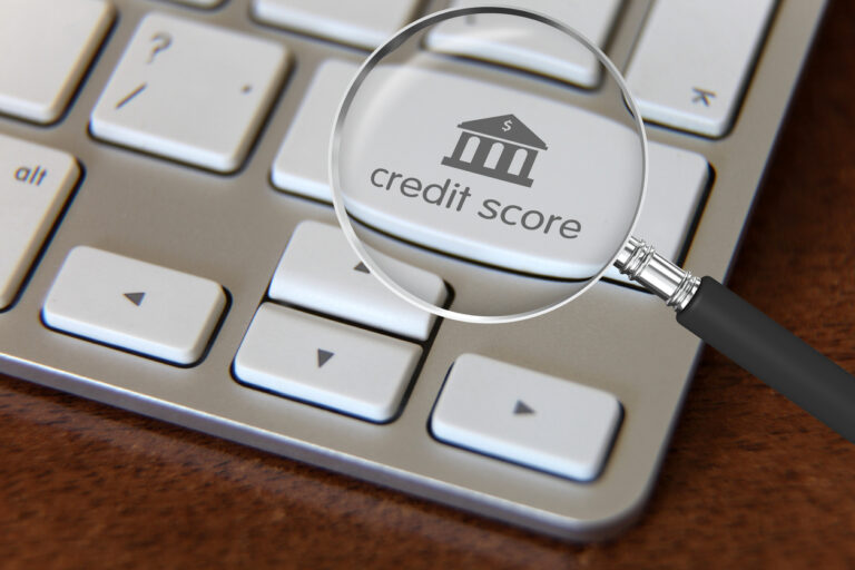 Magnífico destaque para análise de crédito com lupa sobre teclado de computador, apontando importância de avaliação de crédito na obtenção de empréstimos e financiamentos.