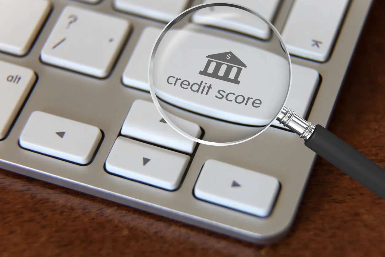 Magnífico destaque para análise de crédito com lupa sobre teclado de computador, apontando importância de avaliação de crédito na obtenção de empréstimos e financiamentos.
