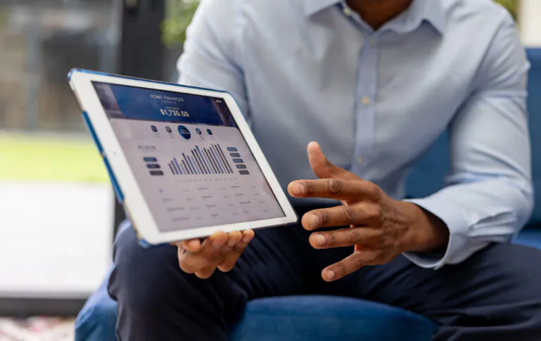 Homem analisa dados financeiros em tablet, representando uma DRE automatizada em tempo real para gestão eficiente de resultados financeiros.