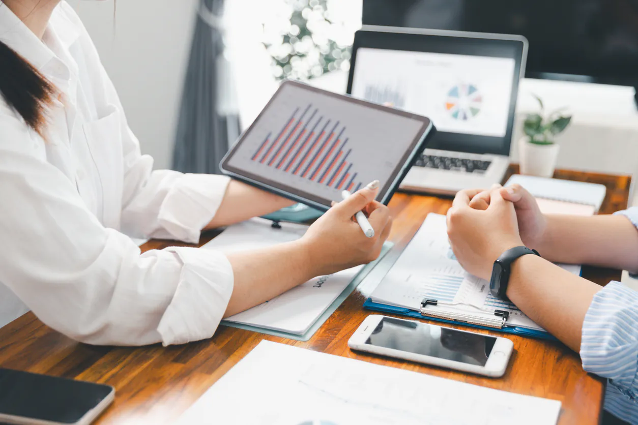 Reunião de profissionais analisando dados de gestão financeira para assessorias de investimento com gráficos e tecnologia.