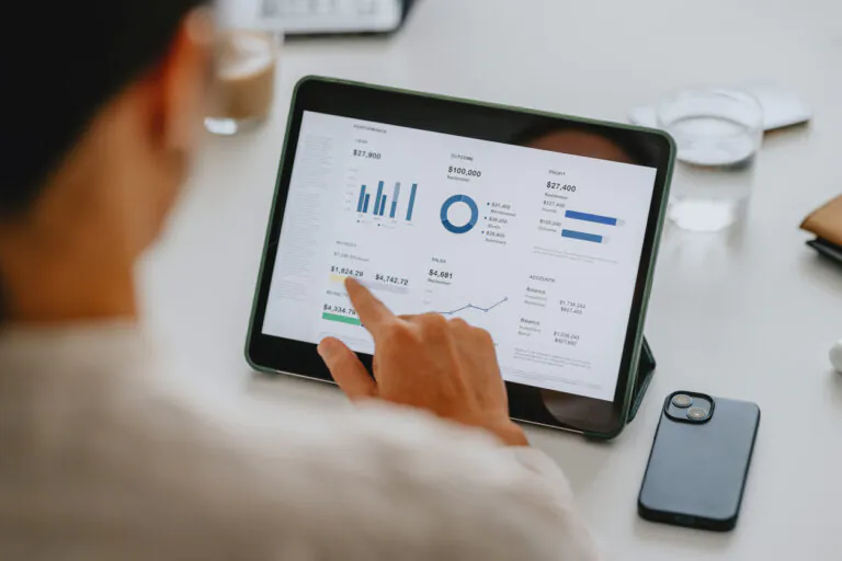 Pessoa analisando dados financeiros e gráficos em tablet que integra software financeiro com banco para facilitar gestão de finanças e contas.