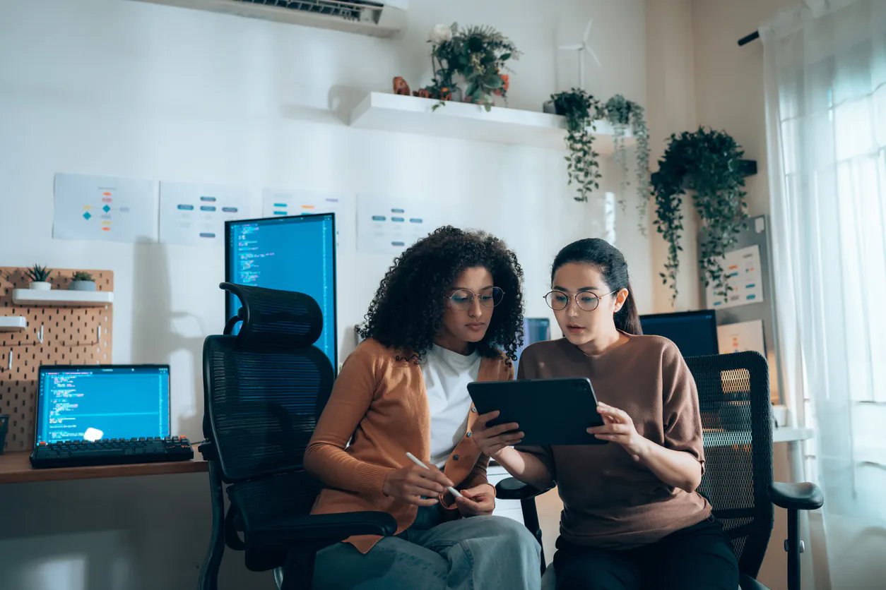 Duas mulheres analisando dados financeiros em um escritório, ilustrando gestão financeira para SaaS com foco em estratégias de negócios e tecnologia.