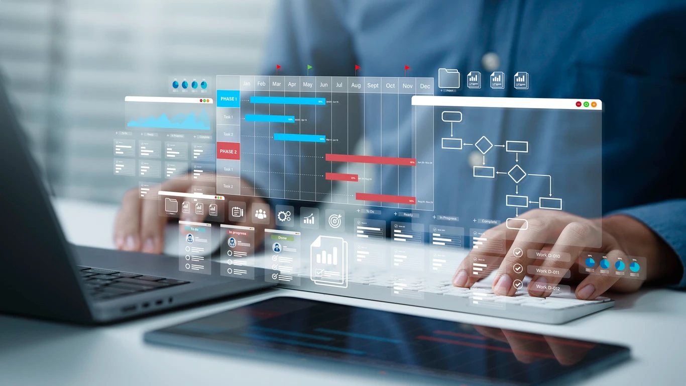 Melhores softwares de fluxo de caixa: pessoa usando notebook com painel de dashboard e gráficos financeiros em múltiplas telas sobrepostas, em ambiente corporativo.