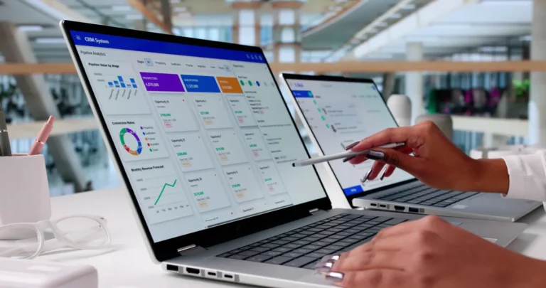 Melhores softwares de gestão de cobranças: Tela de softwares de gestão de cobranças em computadores na mesa de trabalho, com análise de gráficos e relatórios enquanto uma pessoa utiliza o painel no escritório