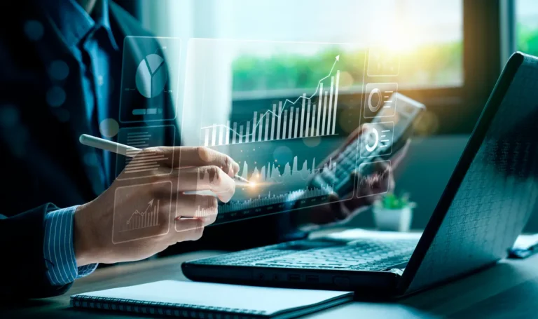 Pessoas analisando gráficos financeiros em um tablet e laptop em um escritório, com indicadores e dados em tela para gestão e planejamento. Melhores softwares financeiros com integrações